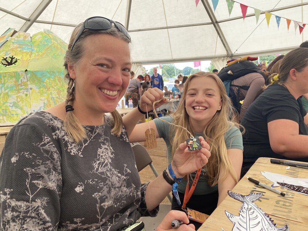 Mother and daughter smiling about receiving a symbol of being safe at a festival 2021