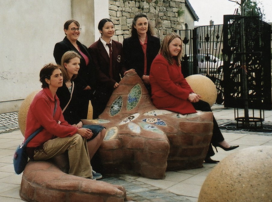 Pupils and teacher sat on a sculpture made by secondary school children