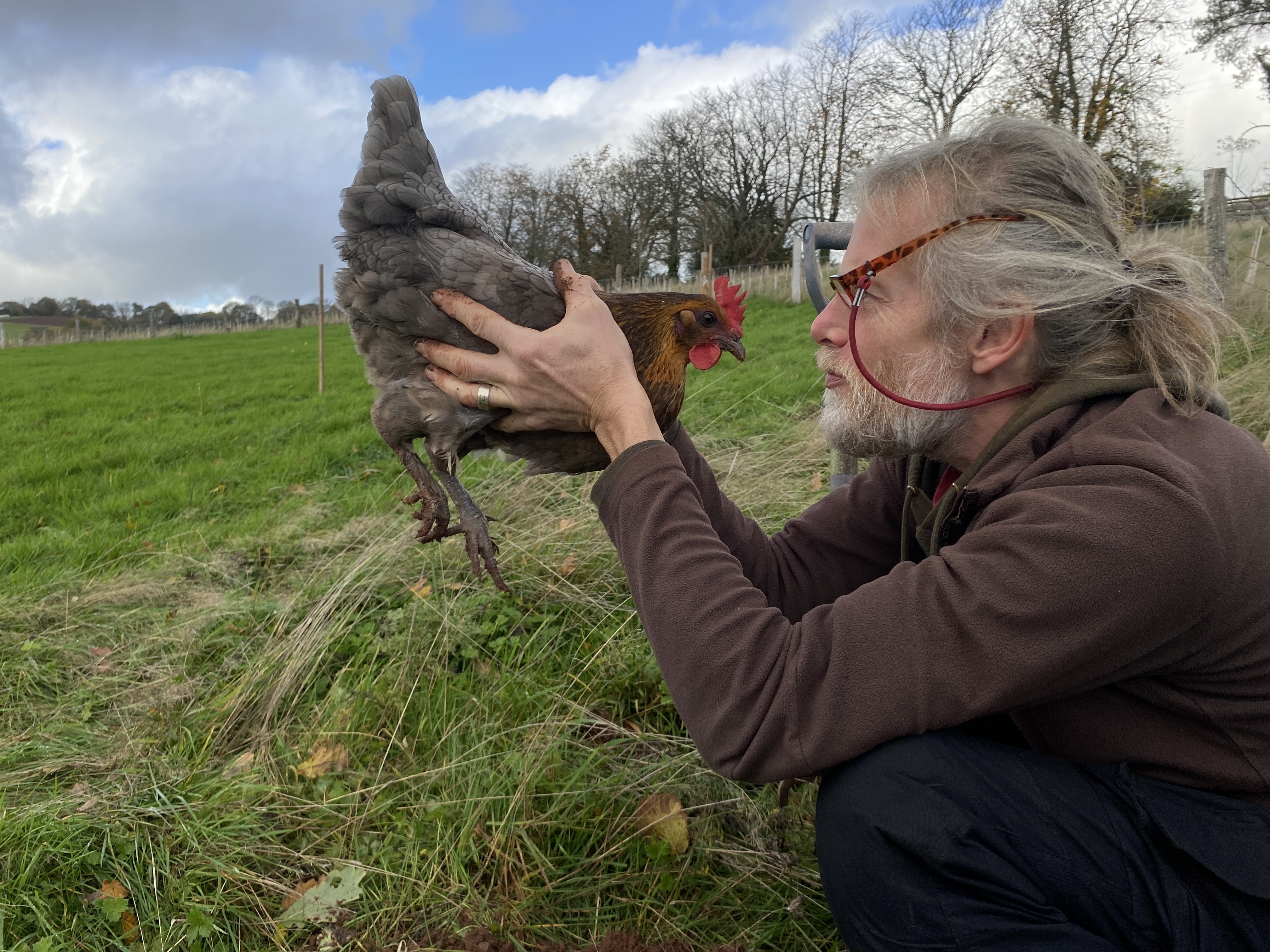 Man holding a chicken staring closely at her
