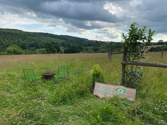 Sign that read Awen Bach, sits with a view of countryside